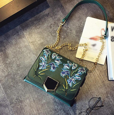 Δερμάτινη τσάντα με ιμάντα ώμου πάνω από τον ώμο του και όμορφα κεντήματα