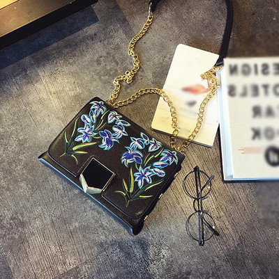 Δερμάτινη τσάντα με ιμάντα ώμου πάνω από τον ώμο του και όμορφα κεντήματα