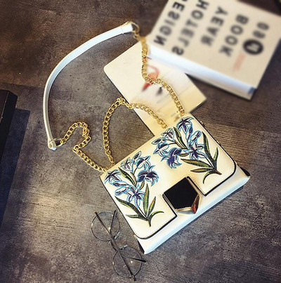 Δερμάτινη τσάντα με ιμάντα ώμου πάνω από τον ώμο του και όμορφα κεντήματα