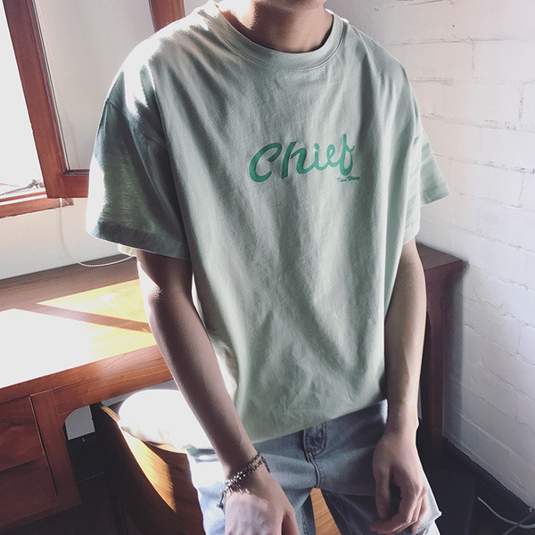 Σύγχρονη αρσενικό ευρύ-shirt με κοντά μανίκια και ένα στήθος επιγραφή