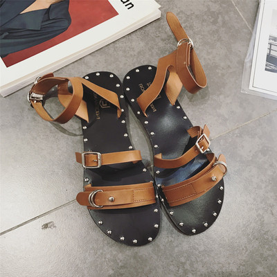 Οι γυναίκες κομψά σανδάλια με λουριά και μεταλλικά στοιχεία σε λευκό, μαύρο και καφέ