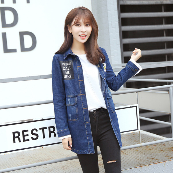 Ένα μακρύ γυναικείο μπουφάν τζην  με μπλε εγχάρακτη επιγραφή