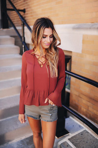 Κομψή γυναικεία μπλούζα σε ένα ευρύ μοτίβο με πέπλα και δεσμούς