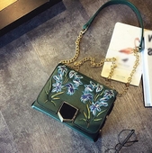 Δερμάτινη τσάντα με ιμάντα ώμου πάνω από τον ώμο του και όμορφα κεντήματα