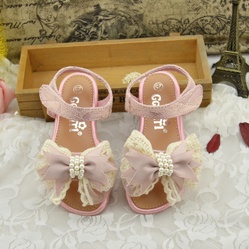 Όμορφη παιδικά σανδάλια για τα κορίτσια με μια μεγάλη κορδέλα και χάντρες σε ροζ και χρυσό χρώμα